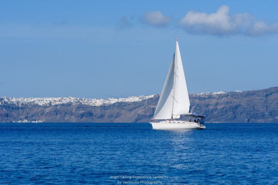 Santorini: Private 5-Hour Sunset Sailing Tour with Dinner - Along the red and white beach, with a lighthouse look-down moment